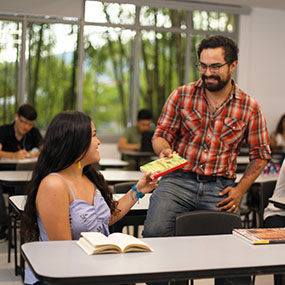 Imagen de profesor recibiendo un libro de parte de una estudiante en la Universidad de Ibagué